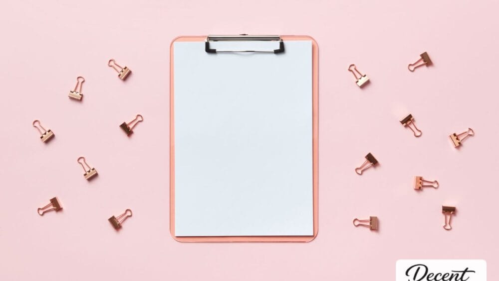 A pink clipboard surrounded by rose gold paper clips on a pink background, Decent Stationery